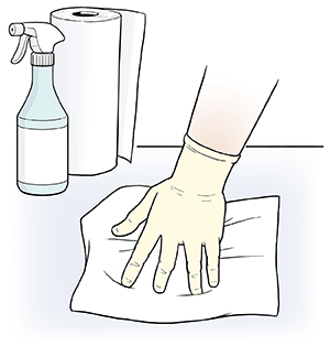 Gloved hand wiping surface with paper towel.