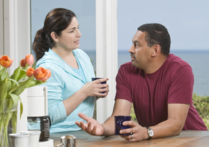 Hombre y mujer conversando mientras toman un café en la encimera de la cocina. 