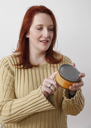 Mujer leando la etiqueta de nutrición de una lata.