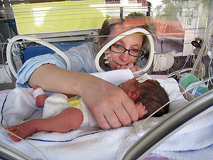 Woman looking at baby in incubator