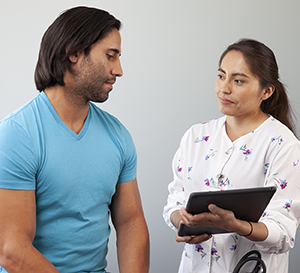 Healthcare provider talking to man in exam room.